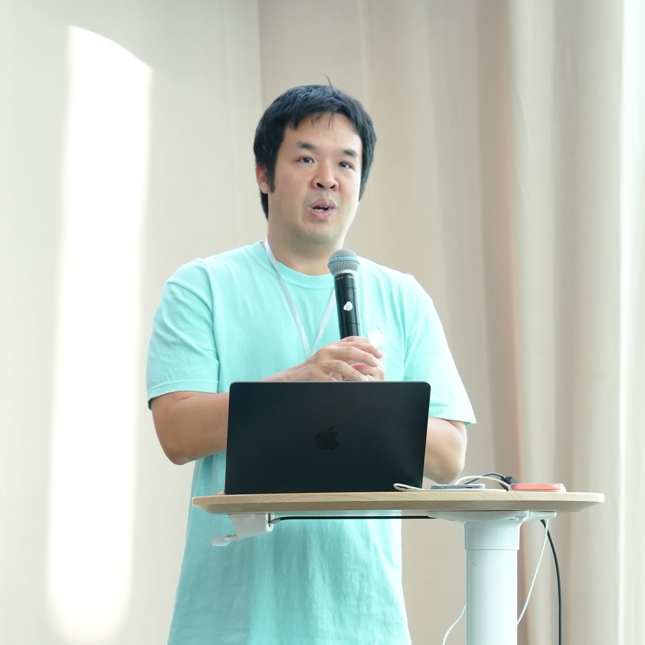 Amorn Apichattanakul giving a tech talk on stage, presenting Building AI-Powered Personalized Mascots in Flutter beside a projection screen